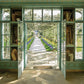 The Garden room opens to a Bunny Mellon-inspired path from the Gardens of Bunny Mellon by Common Ground, bordered with flowers and trees, stretching toward a distant building.