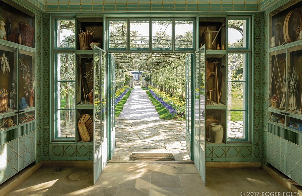 The Garden room opens to a Bunny Mellon-inspired path from the Gardens of Bunny Mellon by Common Ground, bordered with flowers and trees, stretching toward a distant building.