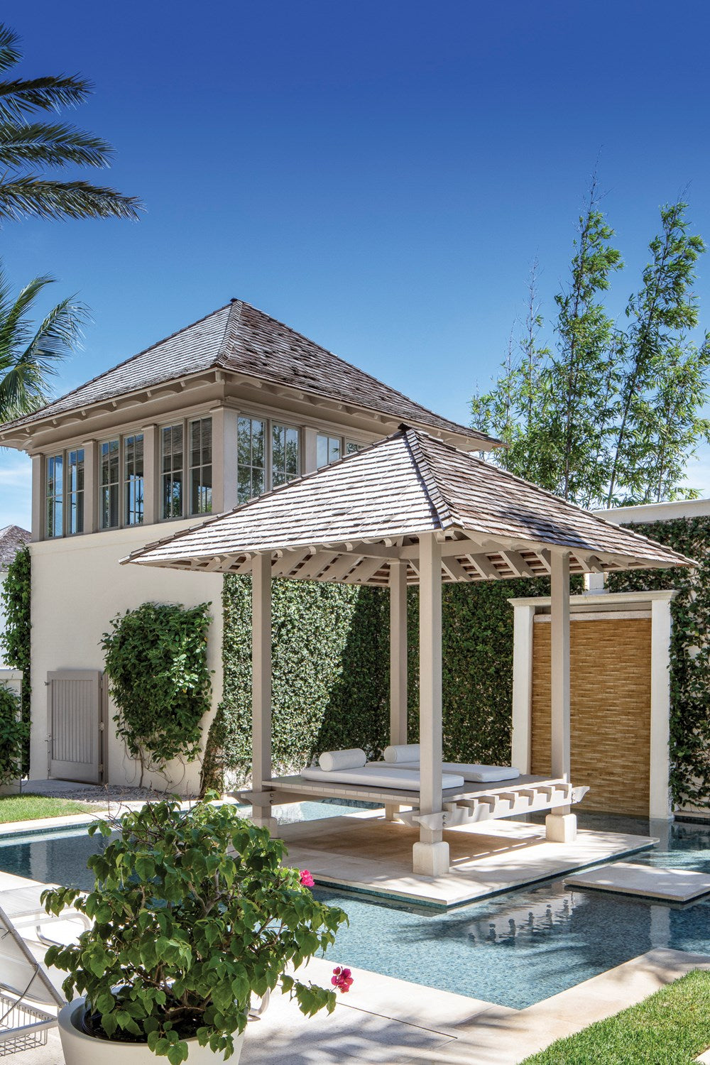 Luxurious poolside pavilion with seating area next to a modern house, embodying the essence of seaside living at Common Ground Vero Beach featuring Beachside: Windsor Architecture and Design.