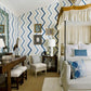 A bedroom adorned with zigzag patterned walls, a white canopy bed, and blue decorative pillows offers an evocative setting. A wooden desk is complemented by white stools and a chair featuring a matching zigzag pillow, embodying the luxurious home interiors depicted in Common Ground's "Atmosphere: The Seven Elements of Great Design.