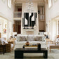 A contemporary living room with high ceilings, white walls, modern furniture, evocative artwork on the walls, and a large fireplace as the focal point embodies the principles of "Atmosphere: The Seven Elements of Great Design" by Common Ground.