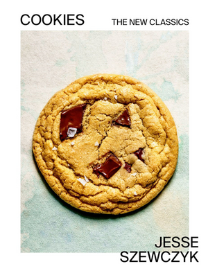 A chocolate chip cookie with flaky salt on a light background. Featured in "Cookies: The New Classics" from Penguin Random House, this treat showcases modern cookie recipes for today’s bakers.