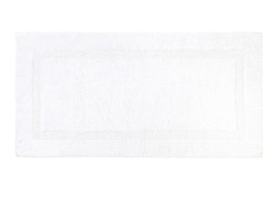 The Yves Delorme Aquilon Bathmat Collection, Blanc is a reversible rectangular cotton bath rug with a textured border design, by Yves Delorme.