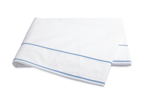 A folded white bedsheet from the Matouk Ansonia Bedding Collection, Ocean, features a light blue stripe near the edge and is made from premium 500 thread count cotton percale, displayed on a plain background.