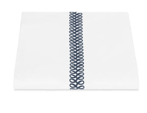 Matouk's Astor Braid Bedding Collection in Indigo features white Ceylon percale with a single vertical navy blue embroidered loop, inspired by Schumacher’s classic design.
