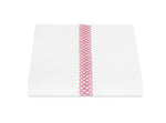 A folded white sheet from the Matouk Astor Braid Bedding Collection in Peony, featuring a vertical pink embroidered loop design, displayed on a white background.