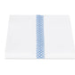 A neatly folded white sheet from Matouk’s Astor Braid Bedding Collection, Sky, crafted from Ceylon percale and featuring a single vertical blue embroidered Astor Braid down the center.