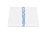 A neatly folded white sheet from Matouk’s Astor Braid Bedding Collection, Sky, crafted from Ceylon percale and featuring a single vertical blue embroidered Astor Braid down the center.