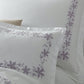 The Callista Bedding Collection, Lilac by Matouk features white Giza Egyptian cotton bedding with matching pillowcases, accented by lilac floral embroidery. This elegant set is OEKO-TEX® certified for safety and quality.