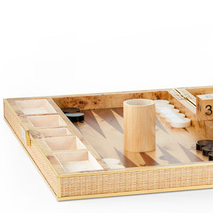 A close-up of the Aerin Cane Backgammon Set, featuring brass hardware, black and white pieces, a dice cup, and dice arranged on the wooden board.
