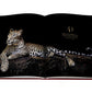 An open book displaying a photograph of a leopard lounging on a rock against a black background features the text "The Panther as Cultural Icon." This striking image captures the essence of modern femininity, reminiscent of the allure and grace found in Cartier Panthere jewelry by Assouline.