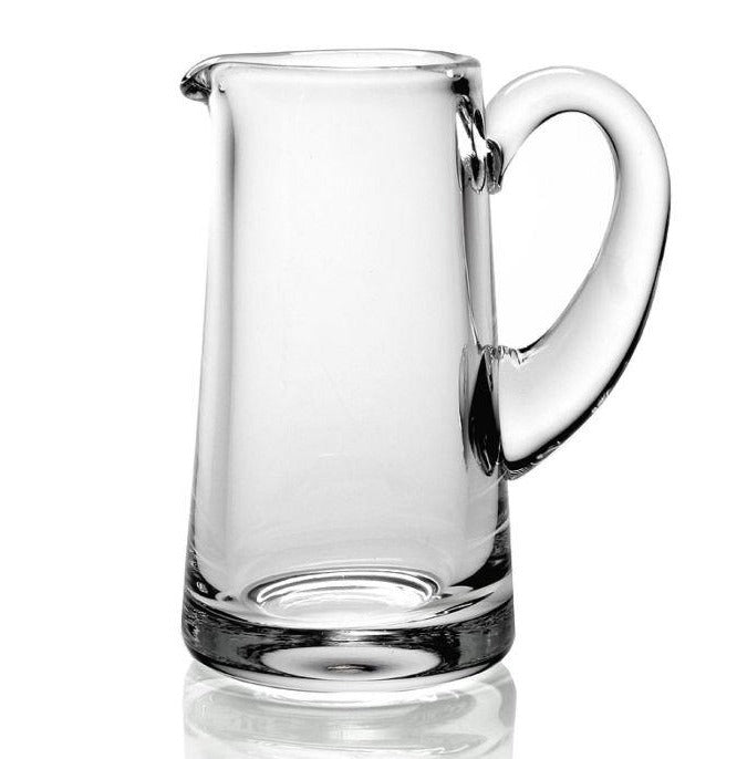 The William Yeoward Crystal Clear Classic Cream Jug is a handmade glass pitcher with a wide base, narrow spout, and large curved handle, ideal for serving berries and cream. Shown here against a plain white background.