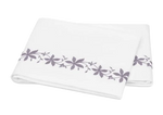 A folded white bed sheet from the Matouk Callista Bedding Collection, Lilac, features lilac floral embroidery along one edge and is crafted from luxurious Giza Egyptian cotton.