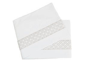 Two plush white folded towels, crafted from luxurious Egyptian cotton with a gray geometric pattern along the edges, rest against a pristine white background. These exquisite towels perfectly complement any piece from the HIVE Exclusive Rovella Bedding Collection by Matouk in Camel.