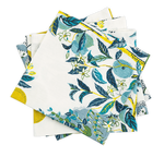 The Matouk Citrus Garden Pool Napkin Set features folded napkins with blue and green floral patterns on a white background, accented with yellow, adding Josef Frank's artistic touch to your table setting.