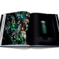 An open fashion book displays a page showcasing colorful jewelry and another featuring a green dress on a mannequin, reminiscent of haute couture designs by Dior IV by Gianfranco Ferré from Assouline.