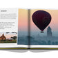 A book featuring a photograph of a hot air balloon soaring over a city, perfect for travel enthusiasts - "Travel by Design" by Assouline.