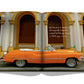 An orange Travel by Design car is parked in front of a building, making it a great spot for photographs.