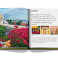 An open book of Travel by Design by Assouline, with a photograph of a city and flowers.