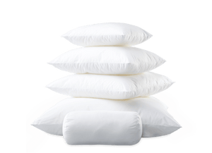 A stack of four square white pillows with a smaller cylindrical Matouk Libero Hypoallergenic Boudoir Pillow Insert in front, all featuring hypoallergenic polyester fill, against a plain background.