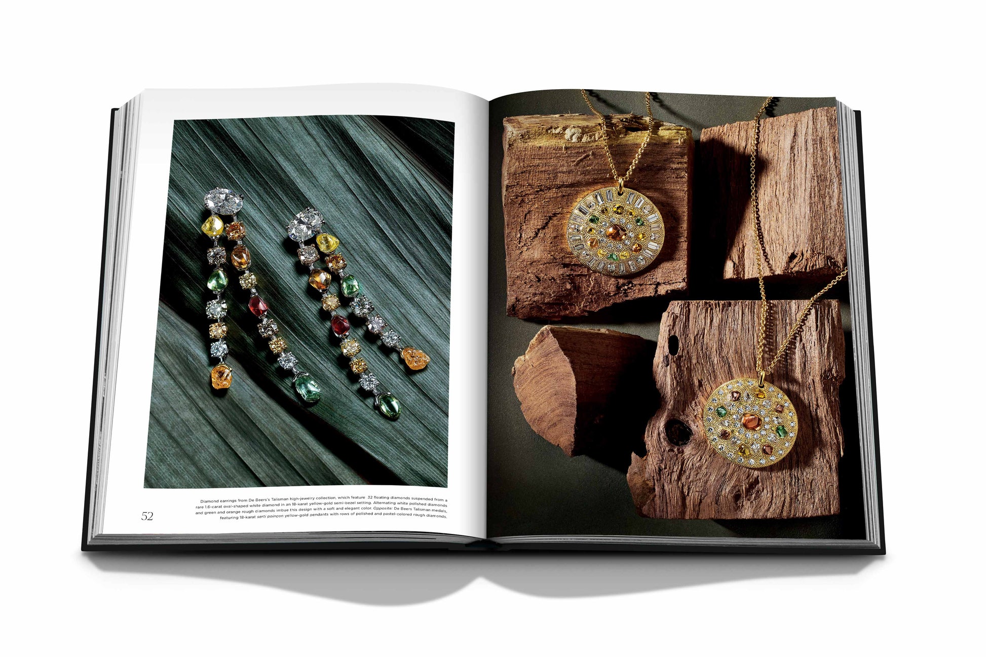 Open book displaying pages with photographs of luxury jewelry. One page shows dangling earrings with colorful gemstones, and the other page features two round pendant necklaces adorned with natural diamonds on a wooden surface. The book "Diamonds: Diamond Stories" by Assouline captures the elegance perfectly.