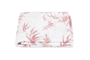 The Matouk Dominique Bedding Collection in Blush features a folded white fabric with a pink botanical leaf and flower pattern, showcased against a plain white background.