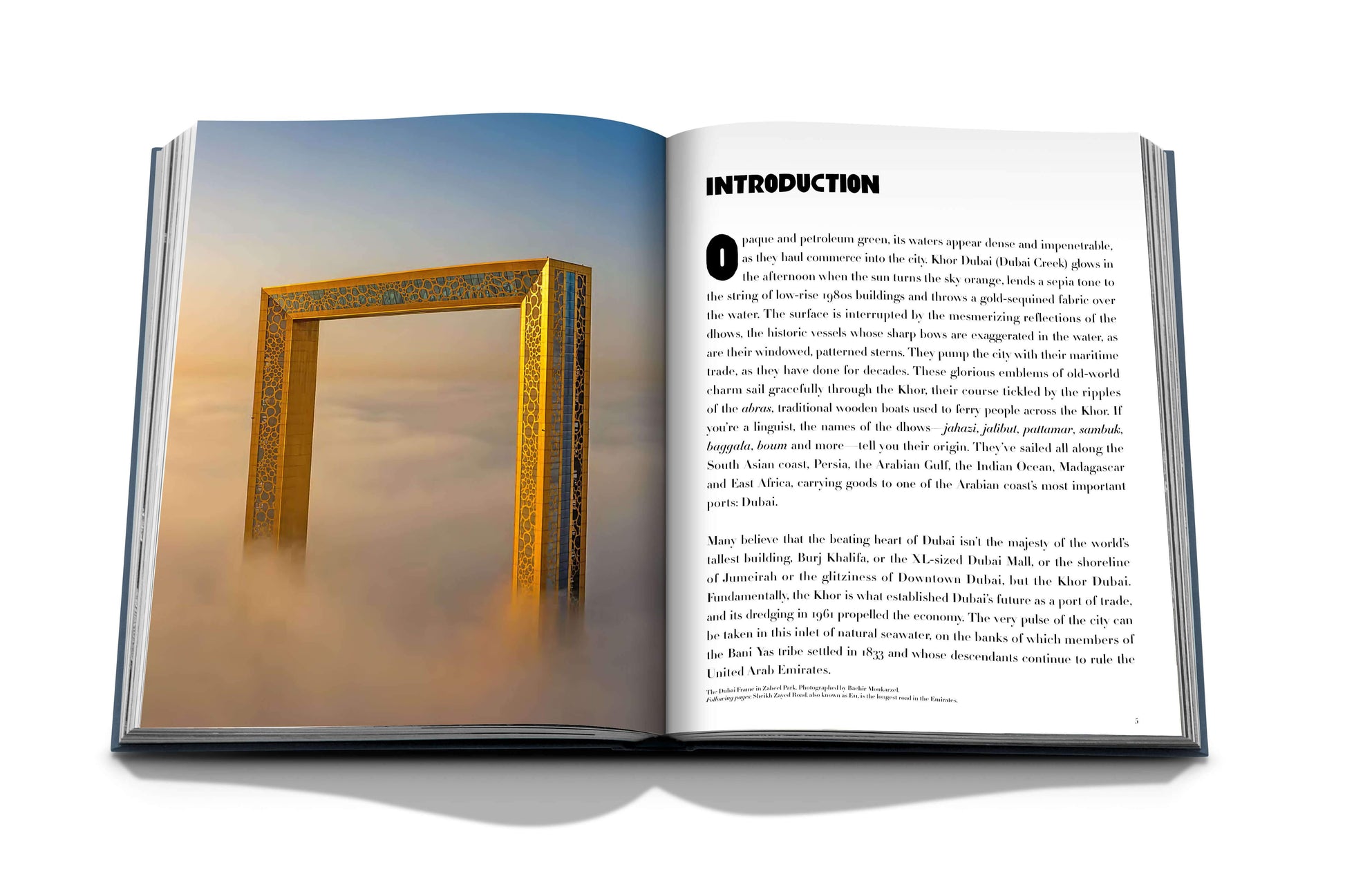 An open book from Assouline titled "Dubai Wonder," featuring a photo of a large, golden frame structure emerging from the clouds on the left page, while the right page displays text titled "INTRODUCTION." The image evokes the grandeur often seen in notable resorts, reminiscent of luxurious tours in Dubai.
