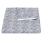 Folded geometric patterned black and white blanket with a corner flipped, showcasing a grid-like design. Part of the Matouk Duma Diamond Bedding Collection in Navy, this blanket is crafted from luxurious Luca Egyptian cotton percale at 500 thread count, seamlessly combining elegance and comfort.