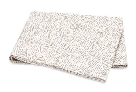The Matouk Duma Diamond Bedding Collection in Dune features OEKO-TEX® certified Egyptian cotton percale with a subtle harlequin pattern on a light, white background.