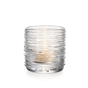 The Simon Pearce Echo Lake Tealight, crafted by master glassblowers, sits lit in a clear, ribbed glass holder against a white background.