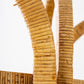Close-up of a beige handle on the Florida-Style Rattan Etagere by HIVE Home, Gift, and Garden, featuring a textured, woven pattern and illuminated by natural light against a white background, reminiscent of the Palm Beach coastal style.