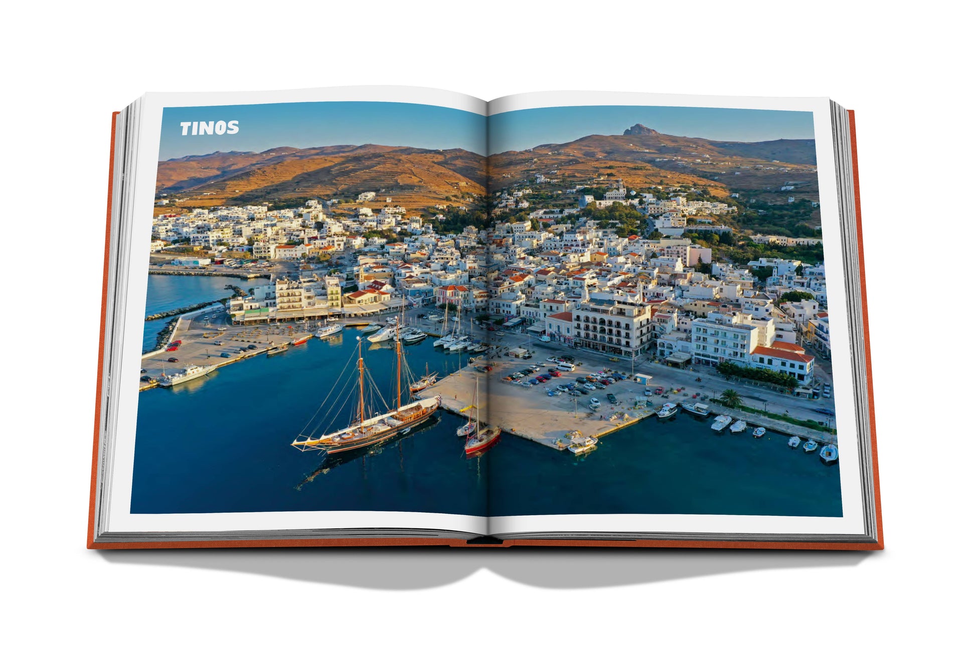 Opened Assouline travel book displaying a panoramic view of Tinos, one of the Greek Islands in the Aegean Sea, Greece.