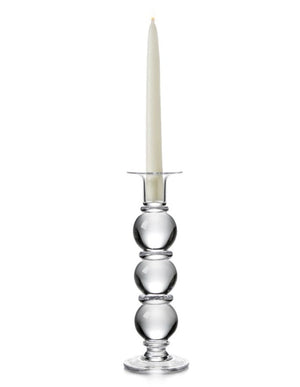 A tall white taper candle sits in the Simon Pearce Hartland Large Candlestick, featuring three glass spheres, handcrafted by artisans and shown against a white background.