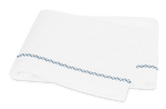 White towel with blue Matouk Hatch Bedding Collection Navy stitching embroidered edge folded on a plain background.