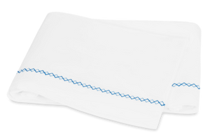 Matouk Hatch Bedding Collection, Sky cloth napkins with a blue zigzag pattern on the edges, featuring French knot stitching, set against a white background.