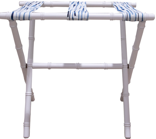 A Sorella Glenn White Luggage Rack in Fern River Blue, folded and standing against a white background on a maple hardwood floor.