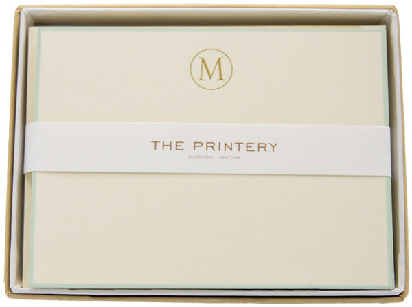 An ecru Printery note card with the initial "M" inside a box.
