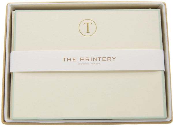 An engraved notepad initial on a Printery - T-Initial Letter with Aqua Border Note Card Box Set placed inside a box.