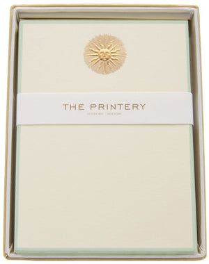 The Printery's Note Card Box Set features vertical ecru cards with a gold embossed sunburst, elegantly packaged.
