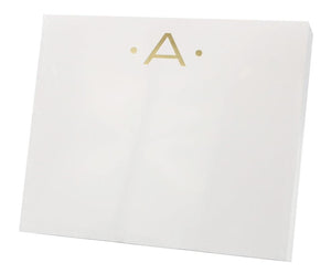 The Gold Initial Large Notepad by Black Ink features a white rectangular box with a gold letter "A" and two gold dots on the front, crafted from high-quality heavy weight paper.