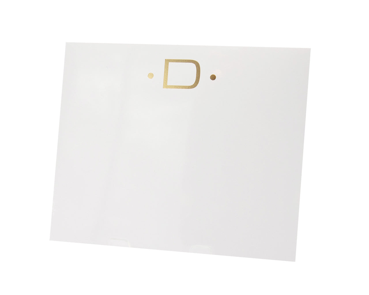 The Gold Initial Large Notepad by Black Ink features a white square design with a gold letter "D" between two gold dots, crafted for an elegant and superior-quality finish.