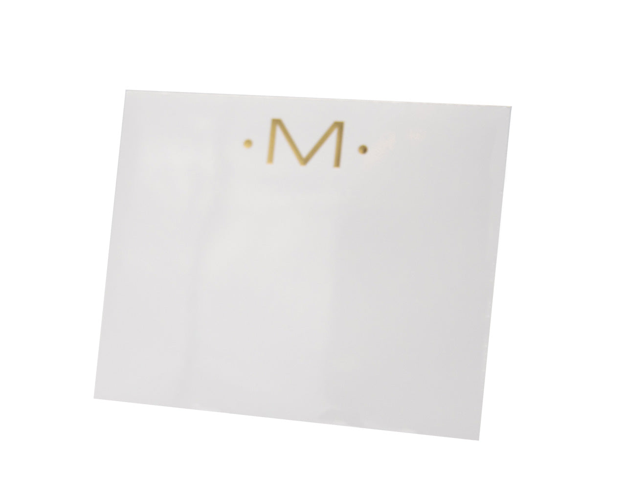 The Gold Initial Large Notepad by Black Ink features a white square design on heavy, velvety paper with a gold "M" centered near the top, accented by two small gold dots.