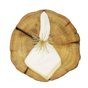 A white cloth napkin with gold trim and a decorative ring rests on the Kim Seybert Woodland Placemat, showcasing country charm—perfect for a nature-inspired luncheon or rustic tablescape.