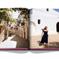 Open book displaying a photograph of a woman walking through a sunlit Mediterranean alleyway in Ibiza, framed by white buildings from Assouline's Ibiza Bohemia.