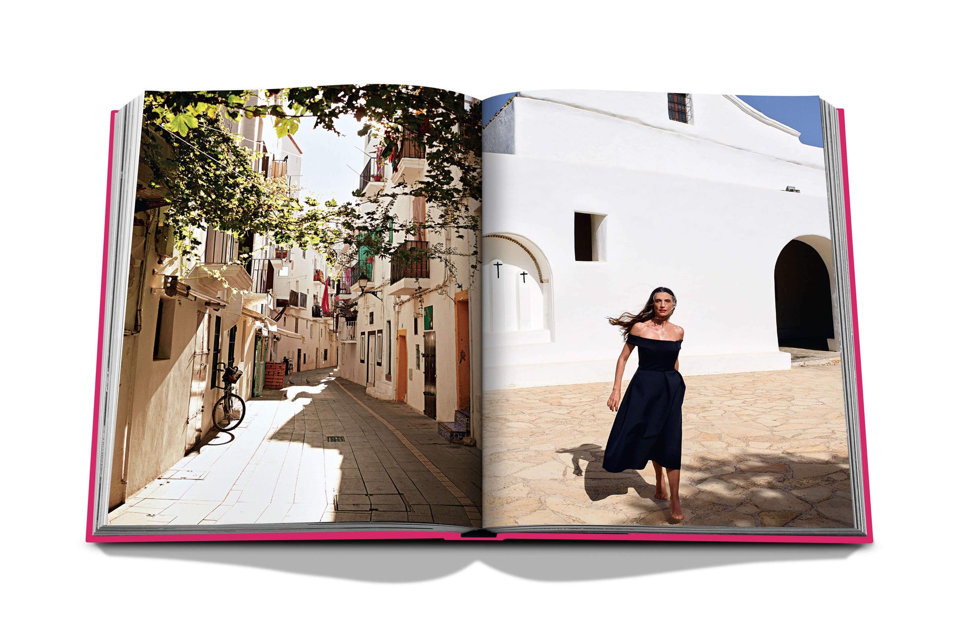 Open book displaying a photograph of a woman walking through a sunlit Mediterranean alleyway in Ibiza, framed by white buildings from Assouline's Ibiza Bohemia.