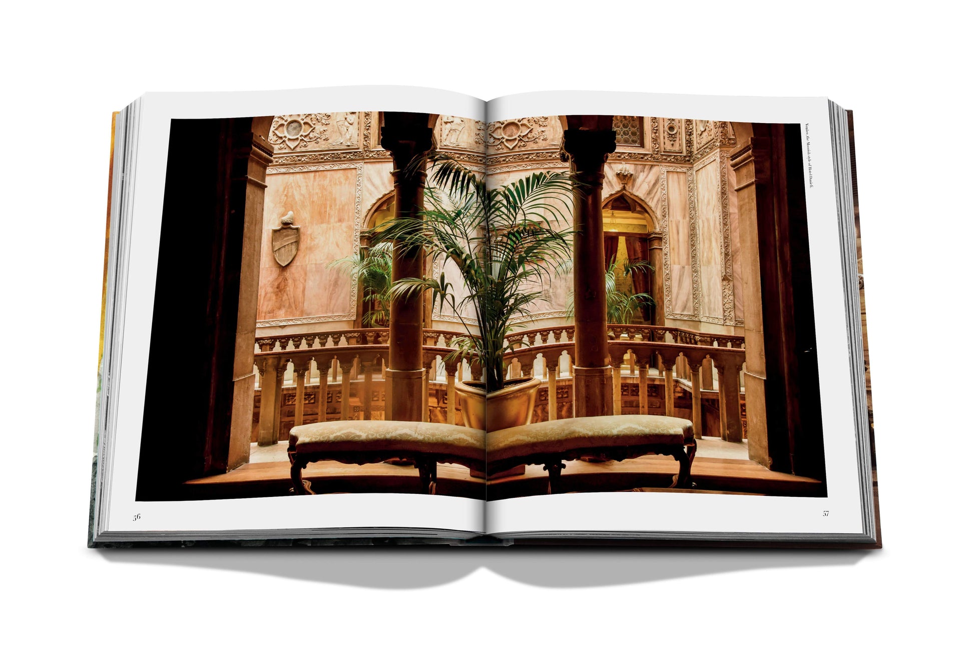 An open book displaying an ornate indoor setting with carved wooden pillars, intricate wall designs, and two cushioned benches facing a potted plant, capturing the timeless Italian style reminiscent of hidden side streets: "Italian Chic" by Assouline.