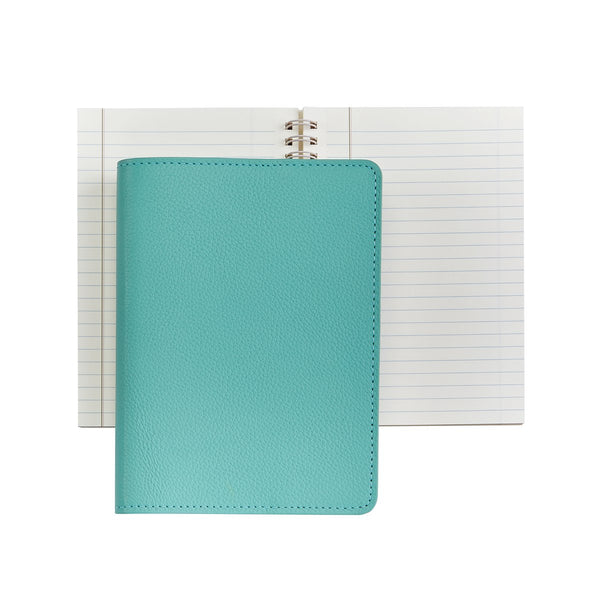 A closed Graphic Image Leather Wire Ring Notebook, Robins Egg Blue, 7”, placed on top of an open spiral-bound lined notebook, both against a plain white background. Perfect for journal writing with its premium paper quality.