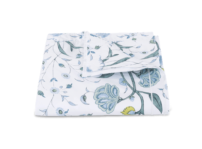 Folded blue and white floral print Matouk Schumacher Bedding Collection, Khilana fabric from the Matouk collection on a green background.