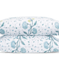 Two white pillows from the Schumacher Khilana Bedding Collection by Matouk, featuring a blue and yellow hand-block floral pattern, are stacked against a plain background.
