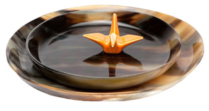 The Lewes Round Tray Set by Pigeon & Poodle features two marbled brown trays made from water buffalo horn, nesting elegantly together with an orange origami crane figurine placed at the center.